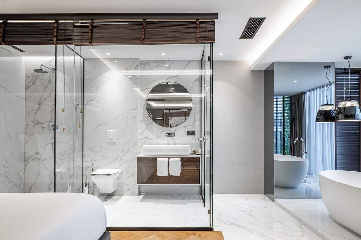 A modern bathroom with a glass-enclosed shower, a freestanding bathtub, and a vanity with a mirror.