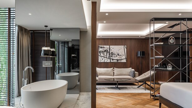 A modern bathroom with a freestanding bathtub, a vanity, and a shower area. - Hotel MANAMI (Pristina)