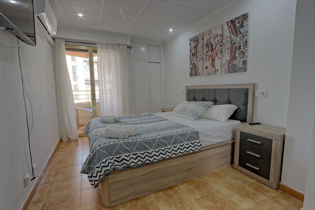 Une chambre à coucher avec un lit, une table de chevet et une fenêtre avec des rideaux.
