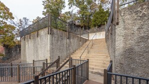 A staircase with wooden railings and stone walls, leading to a higher level.