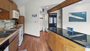 A modern kitchen with wooden cabinets, a black countertop, and a microwave.
