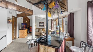 A spacious living area with a wooden ceiling, a bar area, and a seating arrangement.