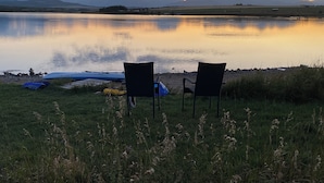 Twee stoelen met uitzicht op een kalm meer, met bergen op de achtergrond.