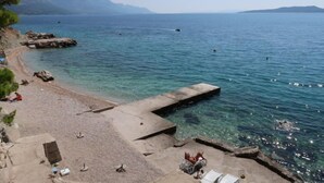 A beach with clear water, a concrete pier, and a few people relaxing. - Vacation home Lada by Interhome (Omiš)