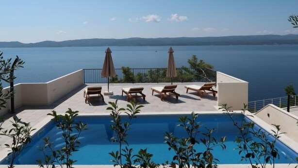 A rooftop pool with lounge chairs and umbrellas overlooking a large body of water. - Vacation home Lada by Interhome (Omiš)