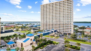 A high-rise hotel with multiple floors, a parking area, and a view of a body of water. - Crystal Tower 1603, Gulf views/ 3 Pools/King Bed (Gulf Shores)