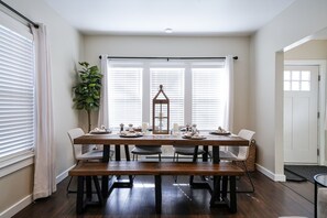 A dining area with a wooden table, four chairs, a bench, and a decorative lantern.