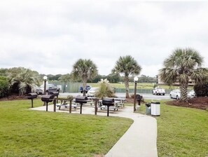 Stroll along the paved walkway to a serene seating area surrounded by lush greenery and palm trees.