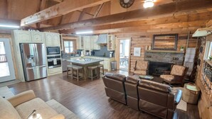 A spacious living area with a fireplace, leather sofas, and a kitchen with modern appliances.