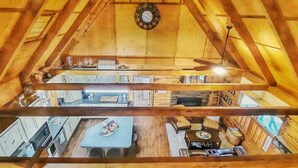 A multi-level wooden interior with a kitchen on the lower floor and a dining area on the upper floor.