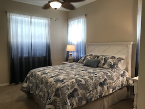 A bedroom with a bed, a nightstand, a lamp, and a ceiling fan.