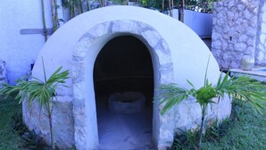 A stone structure with an arched entrance, surrounded by grass and small plants. - Charming 5-Bed Villa in Cancún (Cancún)