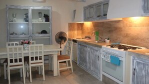 A kitchen with a dining table, chairs, a fan, a stove, and cabinets. - Charming 5-Bed Villa in Cancún (Cancún)