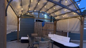 An outdoor patio with a glass table, chairs, and a sofa under a covered area with string lights. - Very Nice Country Stay Not Far Away<br> (New Caney)