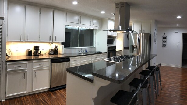 A modern kitchen with white cabinets, stainless steel appliances, and a central island. - Very Nice Country Stay Not Far Away<br> (New Caney)