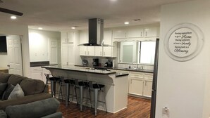 A modern kitchen with white cabinets, a central island with bar stools, and a stainless steel range hood. - Very Nice Country Stay Not Far Away<br> (New Caney)