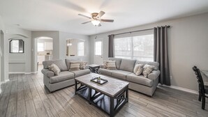 A modern living room with a sectional sofa, a coffee table, and a ceiling fan. - ACL Super Home  . 4 bedroom with Hot spa in the backyard in an awesome neigbohoo (Round Rock)
