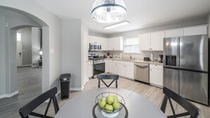 A modern kitchen with white cabinets, stainless steel appliances, and a dining area with a table and chairs. - ACL Super Home  . 4 bedroom with Hot spa in the backyard in an awesome neigbohoo (Round Rock)
