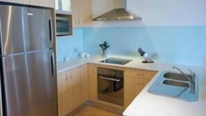 A compact kitchen with a stainless steel refrigerator, a built-in oven, and a sink.