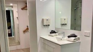 A modern bathroom with a large mirror, white fixtures, and a tiled floor.
