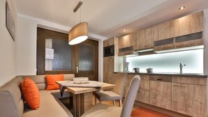 Een moderne keuken met houten kastjes, een eethoek met een tafel en stoelen, en een inbouwoven.