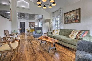 A spacious living room with a wooden coffee table, a green sofa, and wooden chairs. - Sip, Stay & Gather! Vintage Hill Country Bungalow (Fredericksburg)