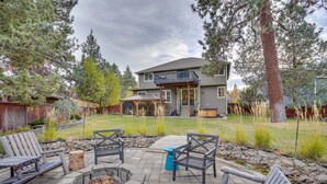 A backyard with a fire pit, outdoor seating, and a house with a balcony.