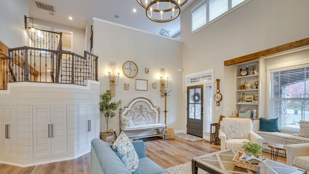 A spacious living room with a staircase, a fireplace, and a seating area with a sofa and chairs.