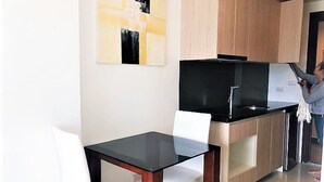 A modern kitchen with a black stove, white chairs, and wooden cabinets. - Laguna Beach 3 The Maldives - top floor studio (Pattaya)