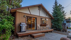 A wooden cabin with a deck, a grill, and a sign indicating a maximum occupancy of 4 cars. - Romantic Couple's Retreat steps from Village, Kid-Friendly, Fireplace, WiFi (Big Bear Lake)