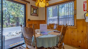 A dining area with a table set for four, a welcome sign, and a view of the outside.
