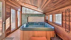 Ein Holzblock-Innenraum mit Whirlpool, großen Fenstern und Holzboden.