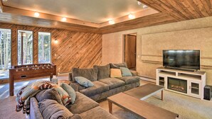 Ein gemütliches Wohnzimmer mit Holzboden, einer großen Couch, einem Fernseher und einem Kamin.