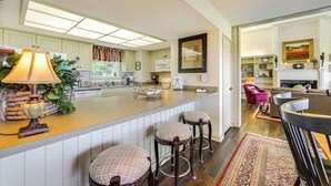 A spacious kitchen with a large island, bar stools, and a dining area with a red chair. - Breathtaking Highlands Condo w/ Mountain View (Highlands)