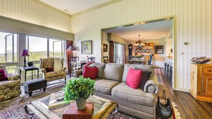 A spacious living room with a large window, a sofa, a coffee table, and a dining area visible through an open doorway. - Breathtaking Highlands Condo w/ Mountain View (Highlands)