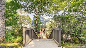 A concrete pathway leading to a building with a glass facade, surrounded by trees and greenery. - Breathtaking Highlands Condo w/ Mountain View (Highlands)