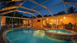 Une piscine avec un patio couvert, un jacuzzi et du mobilier d’extérieur.