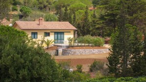 A single-story house with a tiled roof, surrounded by dense greenery and trees. - Independent Villa l'Aia in a panoramic and quiet position on the Gulf of Lacona (Capoliveri)