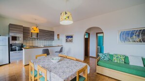 Ein kompakter Wohnbereich mit Küche, Essbereich und einem grünen Sofa.