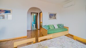 Ein Zimmer mit einem hölzernen Bett, einem grünen Sofa, einem Fliesenboden und einem Bild an der Wand.
