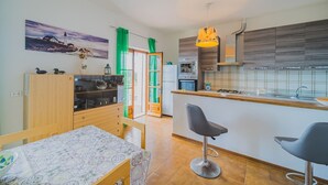 Eine moderne Küche mit einem Holztisch, zwei Barhocker, einem grünen Vorhang und einem Bild an der Wand.