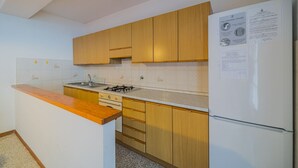 A kitchen with wooden cabinets, a white refrigerator, and a sink. - APPARTAMENTI SANT'ANDREA - CASA GRANDE ALLE PIANE (Marciana)