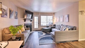 Ein modernes Wohnzimmer mit einer Sofagarnitur, einem Couchtisch und einem an der Wand befestigten Fernseher.