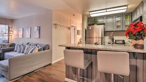Eine moderne Küche mit Bar, grauen Schränken und einem Edelstahl-Kühlschrank.