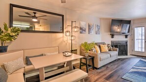 Ein modernes Wohnzimmer mit einer Couch, einem Esstisch, einem Deckenventilator und einem Kamin.