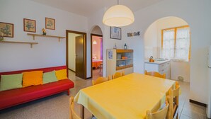 Ein gemütliches Wohnzimmer mit einem roten Sofa, einem gelben Esstisch und einer Küchenzeile mit einem Fenster.