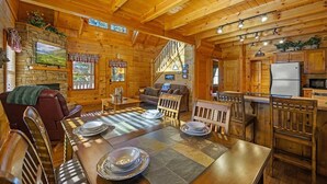 Un intérieur chaleureux de chalet en bois, comprenant un coin repas, une cuisine et un salon.