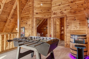 Relax in a rustic retreat with a foosball table and cozy seating area.