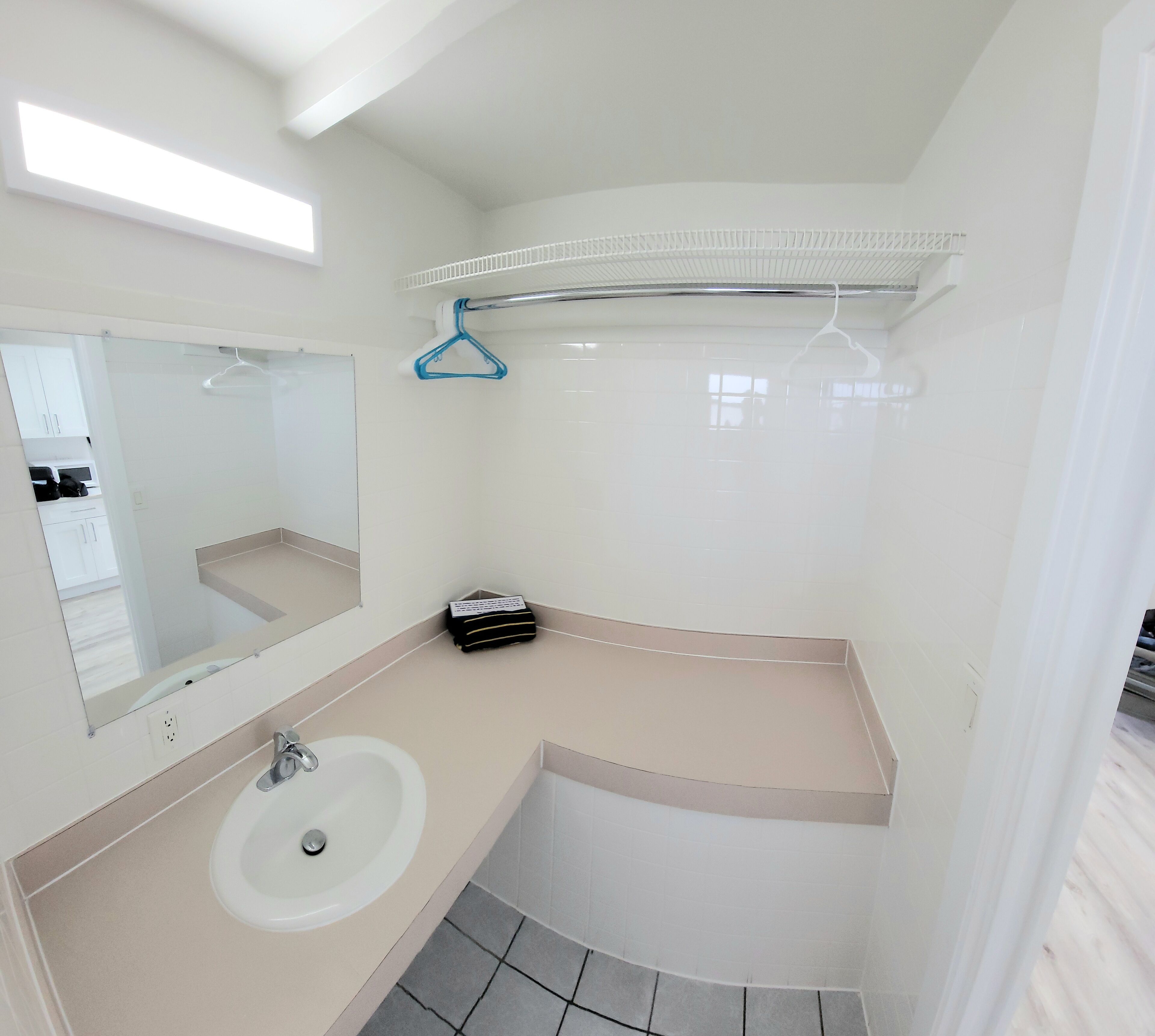 A small bathroom with a white sink, mirror, and a towel rack.