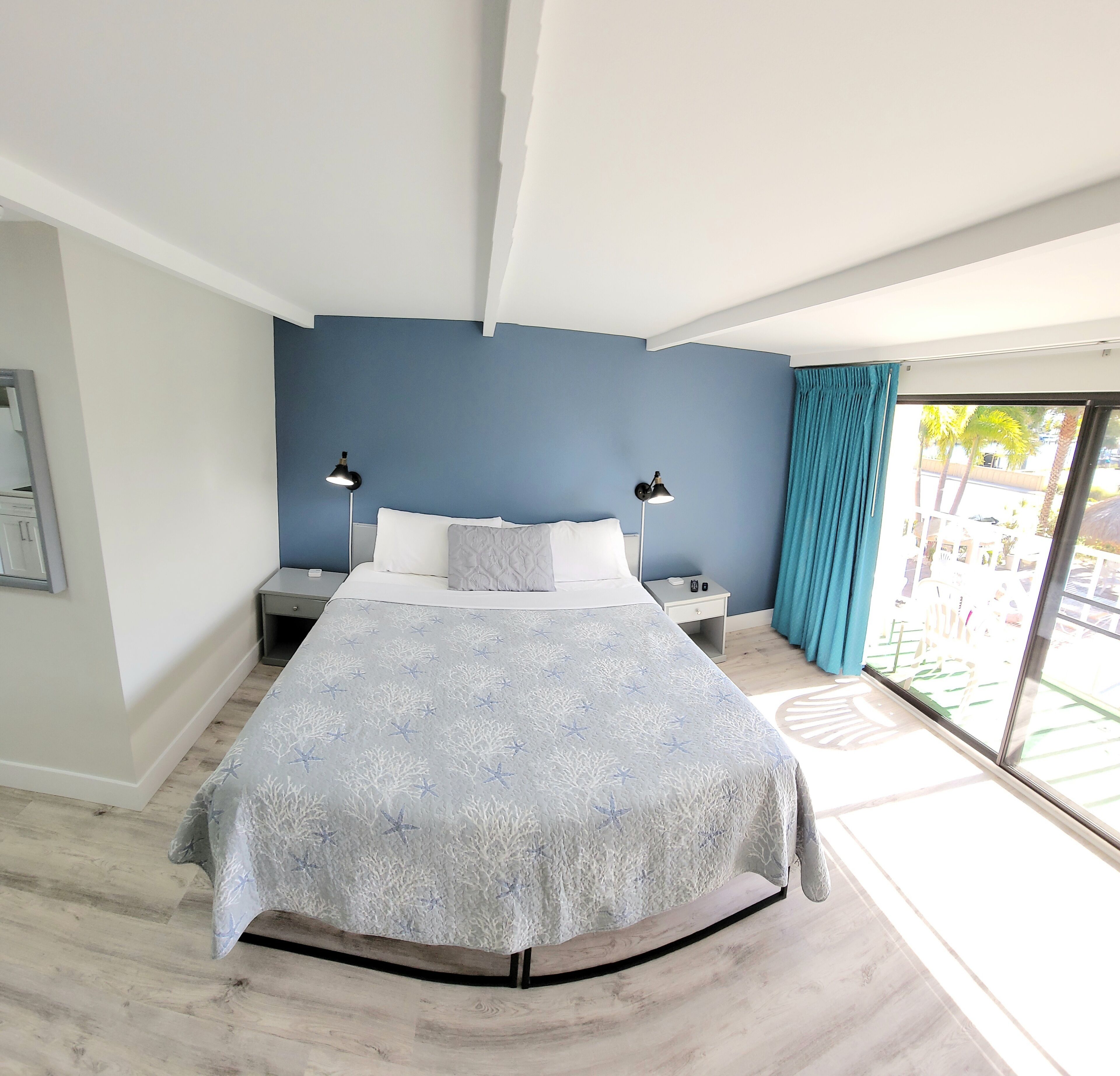 A modern bedroom with a bed, two bedside tables, a nightstand, and a view of the outside.